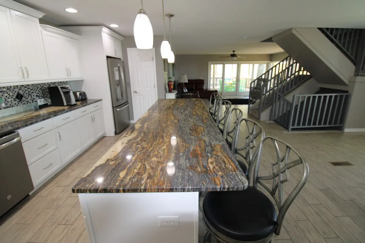 A welcoming kitchen space highlighted by granite countertops, stylish bar stools, modern cabinetry, and contemporary lighting fixtures. The seating at the island encourages conversation during meal prep and casual coffee chats.