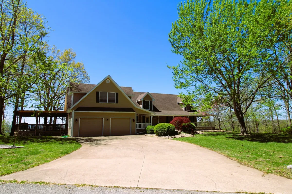 This exterior image features the home's welcoming facade, the driveway, and the surrounding trees. The porch is visible, hinting at a relaxing area perfect for group gatherings or unwinding after a day of adventure at nearby attractions.