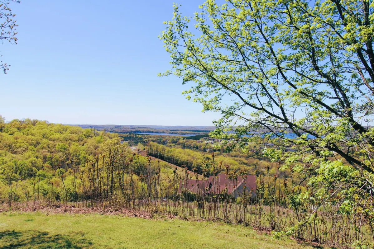 An expansive view of green hills, distant valleys, and leafy tree branches under a clear blue sky. This perspective evokes the natural beauty surrounding the area and the opportunities for group exploration beyond the home itself.