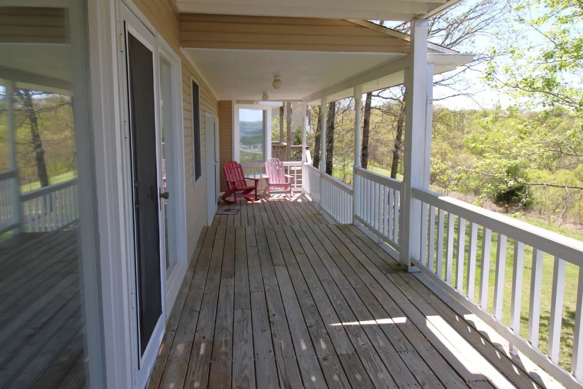 A peaceful wooden deck with red Adirondack chairs offers a beautiful spot to relax, read, or recount the day's adventures. The view of the surrounding nature creates a sense of escape and tranquility, perfect for unwinding.